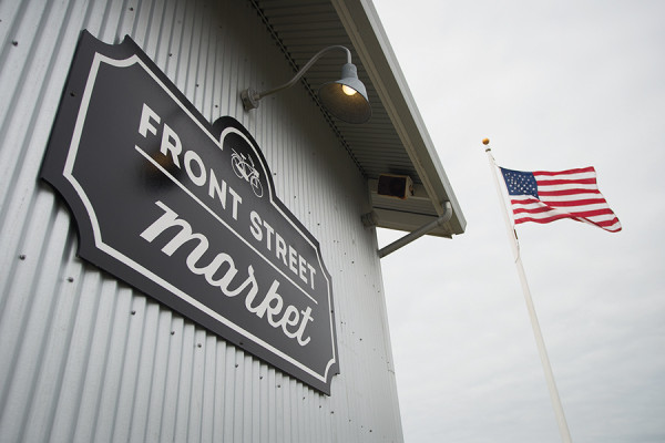 (Aaron Lavinsky | The Daily World) The American flag flies behind a Front Street Market sign in Seabrook.