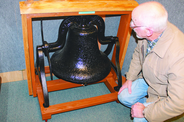 Angelo Bruscas photo/Jerry Mergler, a Coastal Interpretive Center volunteer, inspects the Coast Guard bell he helped to restore. The bell was used to warn the area in the event of a Japanese attack by sea during World War II.